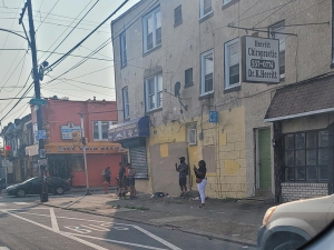 People standing on the corner of Bridge Street in front of Herritt Chiropractic in Philadelphia. In this neighborhood, residents looking to get cash for home in Wissinoming use Joey Loves Philly to close fast and easy.