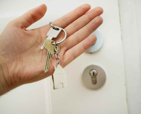 Hand holding a house key for a door. When asking cash for house Philly homeowners can sell quickly.