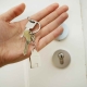 Hand holding a house key for a door. When asking cash for house Philly homeowners can sell quickly.